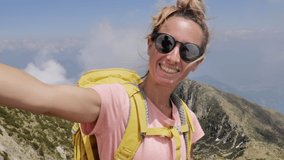 Young woman on a hike takes cool selfie on mountain top. Female adventures takes selfies on a hike 