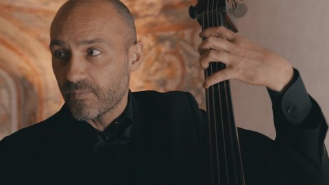 A male cellist plays his cello intently with a string quartet
