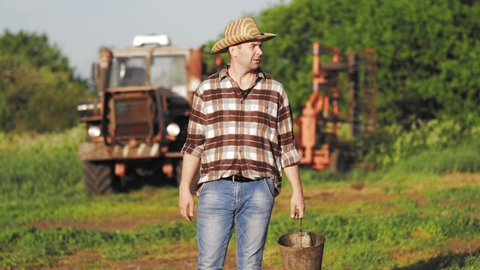 Farmer with his tractor. Handsome man next to an old tractor. Middle aged farmer looking away at farmland.