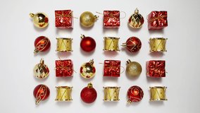 Wave motion of bright toys for a Christmas tree on a white background, stop motion animation of red and gold Christmas balls, New Year's gifts and drums, 4K video, loop.
