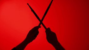 Drummer Beats Rhythm With Drumsticks On Red Light Background