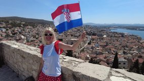 Woman waving a Croatian flag on the St. Michael Fortress, over the port of Sibenik city with boats and cruise ships. Sibenik historic city of Croatia in Dalmatia. It was part of the Venice Republic. - Powered by Shutterstock - Get 15% off with code: PIKWIZARD15