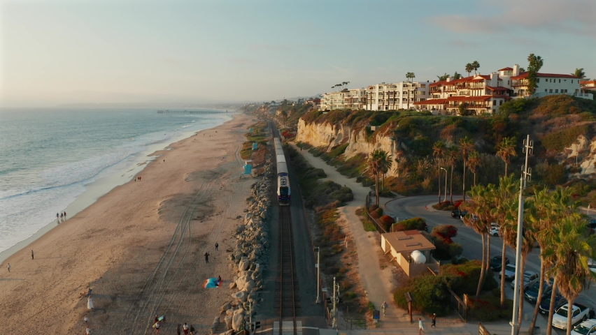 Aerial view following behind an Amtrak train along the coast in San Clemente, California