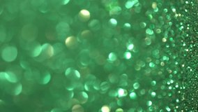 Green Glitter Background. Light bokeh, magic christmas lights. Shiny texture, holiday lights, flying particles form a beautiful bokeh. Shining festive Christmas backdrop. Vertical Video