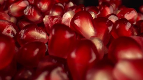Ruby-colored flesh covers the seeds of pomegranate fruit. Soft light is reflected on the glossy surface of the fruit. Pomegranate for juice preparation. High quality. 4k footage.