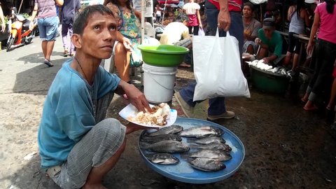 LAGUNA, PHILIPPINES - JULY 16, 2015: Tilapia fish sold at street wet market while eating lunch due to lack of market hygienic facilities