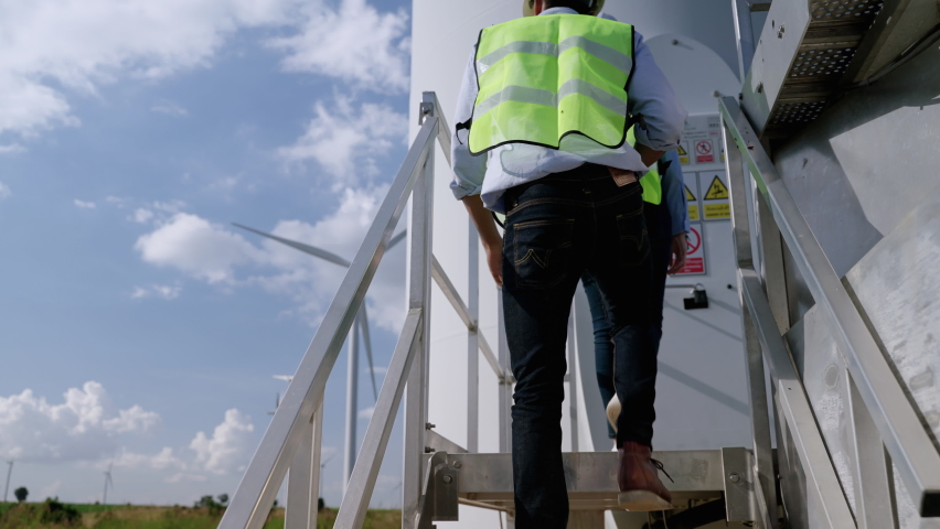 Two engineers are standing together discussing wind power projects and work in a wind turbine field, clean energy concept, renewable energy, save the world. Royalty-Free Stock Footage #1082193299