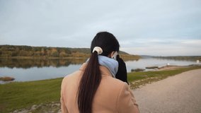 An HD video of an adult Caucasian woman walking at the lakeside and talking on a smartphone in Lithuania