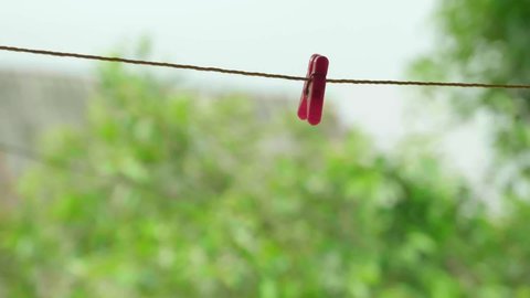 4K video of colorful clothespins on a rope in the garden with green background.