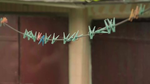 4K video of colorful clothespins on a rope in the garden with green background.