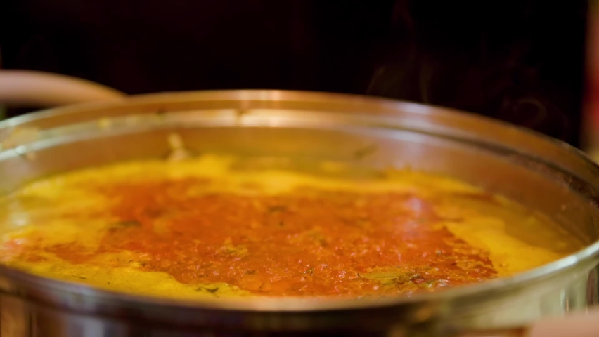 steam and vapour rises from hot soup in a saucepan - close-up with selective focus slowed down four times
