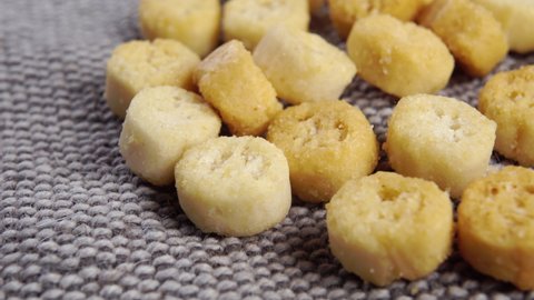 Round small croutons on a rough jute burlap close up. Crunchy salad ingredient. Macro. Dolly shot