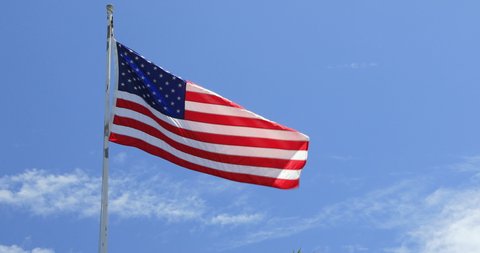 Stationary handheld footage of flag blowing in the wind with blue sky background, Hawaii, USA