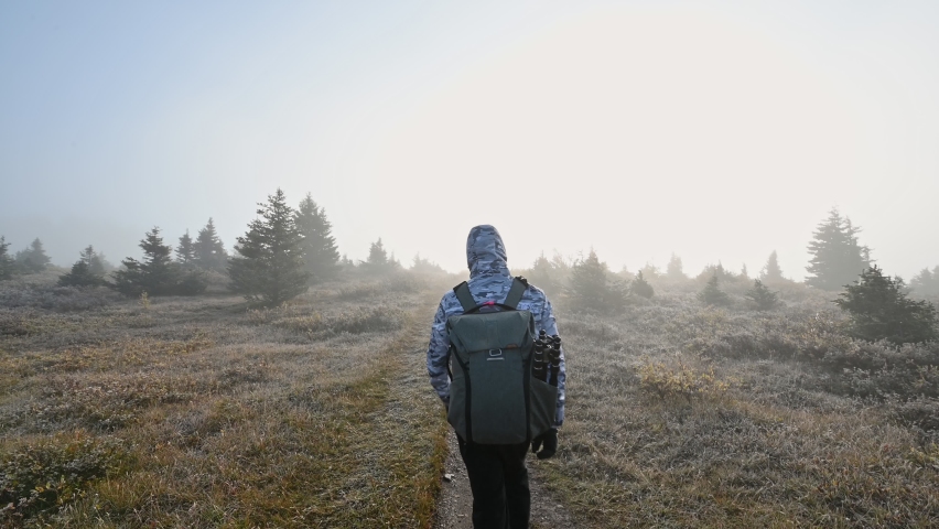 Man photographer walking in foggy on autumn forest with sunshine at morning