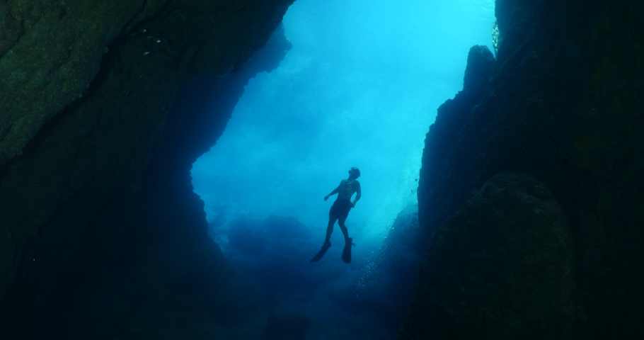 free diver in acave underwater going out of the cave in blue light ocean topography and human scenery of sports Royalty-Free Stock Footage #1082201660