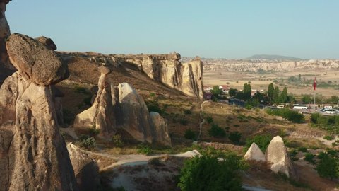 Aerial flyover above incredible tall rocks and small town, happy couple enjoying amazing view in Cappadocia, Turkey.
