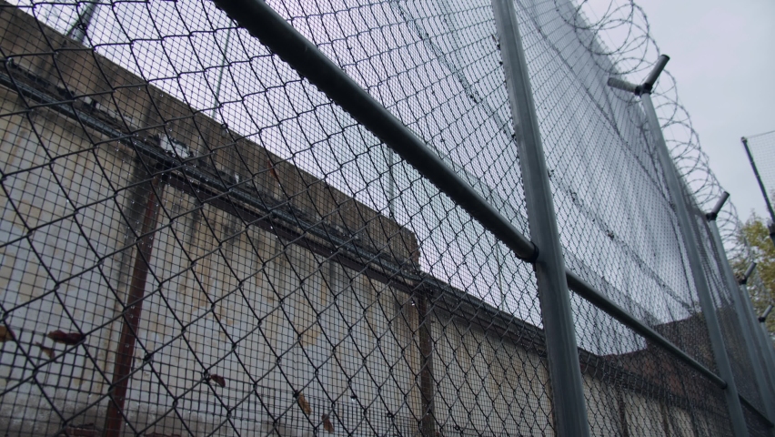 Overview of the electric chain-link fence with barbed wire of the prison on a rainy day. Drops of rain on the fence. Royalty-Free Stock Footage #1082208305