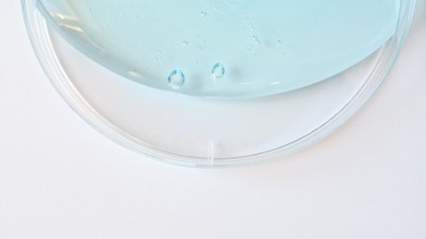 Blue Transparent Cosmetic Gel Cream With Molecule Bubbles Flowing On The Plain White Surface. Macro Shot