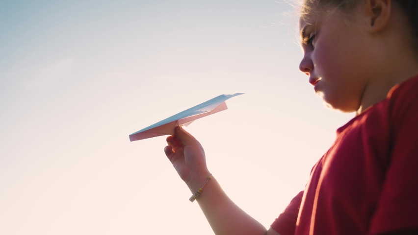 girl kid play in the park across the field with an paper toy airplane. baby his hand paper plane silhouette at sunset. wants to astronaut pilot fun. fantasy dream kid concept. child play fun with toy