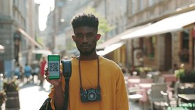 African american man with backpack standing on city street and holding smartphone with health passport on screen. COVID 19 vaccination status. Ability to travel during coronavirus pandemic . - Powered by Shutterstock - Get 15% off with code: PIKWIZARD15