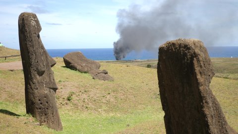 Mysterious Moai statues on fire. Ancient statues made of black volcanic rocks under the inactive volcano on Easter Island. exotic island landscape and Giant megalith Moai statues. 4K Rano Raraku.
