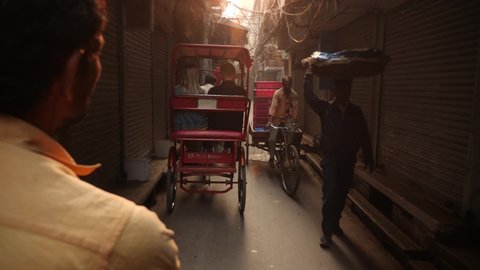 Delhi, India - Nov 12 2021: Morning Bicycle Rickshaw ride through narrow streets of chandni chowk in old delhi, india. Morning life in Chawri bazar. Street of Old Delhi. Chaotic scene inside old Delhi
