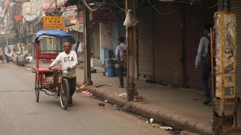 Delhi, India - Nov 12 2021: Bicycle Rickshaw ride at morning chandni chowk in old delhi, india. Morning road traffic in Chawri bazar. Street of Old Delhi. Chaotic scene inside old Delhi.