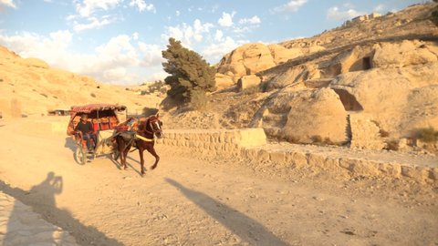 Petra, Jordan - Nov 12 2021: Bedouin riding a horse and carriage ride. Horse carriage on stone road during a sunset.