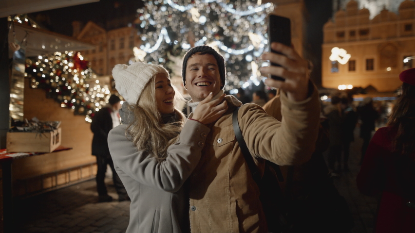 Mixed race couple taking selfie at night market in Prague. Love, family, christmas, new year, holiday concept. Filmed on RED camera, 10 bit clolor
