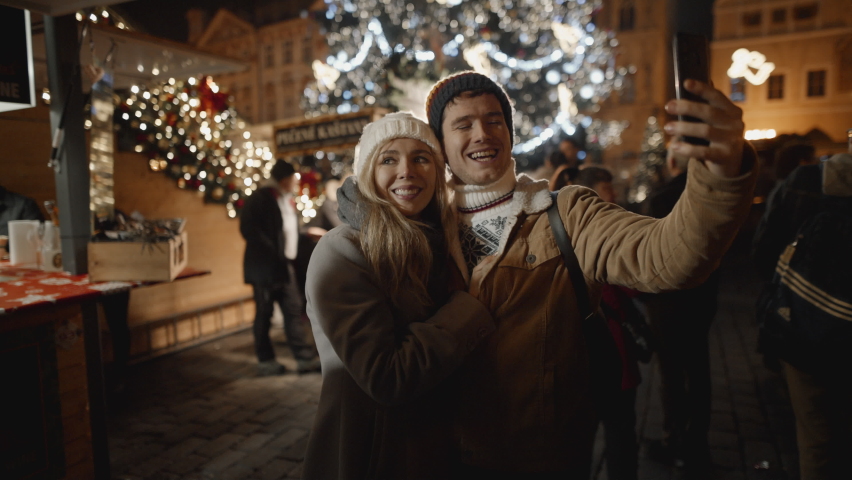 Loving couple taking selfie at night market in Prague. Love, family, christmas, new year, holiday concept. Filmed on RED camera, 10 bit clolor