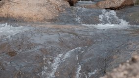 Slow motion video of the river flowing through the rocks.