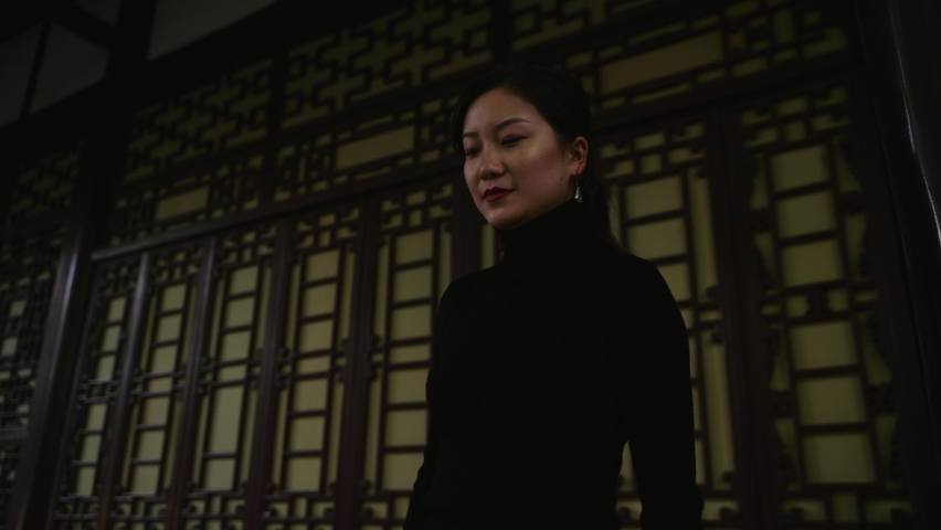 Happy Asian woman walking in a park in Chengdu young woman in a black sweater is visiting a Chinese style building people travel lifestyle