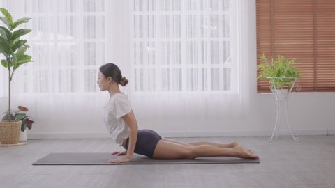 Asian woman practising yoga, Cobra exercise, Bhujangasana stance, working out, and wearing sportswear.