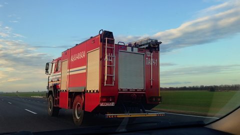 Grodno, Belarus - 11 12 2021: Handheld shot of fireman rescuers driving on rural road with turn on signal lights