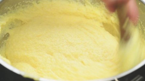 Cooking and stirring polenta in a saucepan.