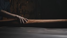 Shoes production. Unrecognizable man shoe maker rolling out piece of leather for cutting needed amount to make boots at workshop, close up, tracking shot - Powered by Shutterstock - Get 15% off with code: PIKWIZARD15