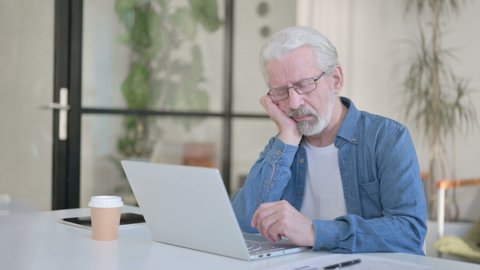 Senior Old Man Taking Nap while using Laptop in Office 