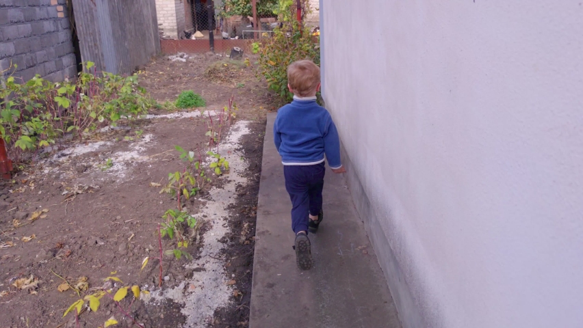 Boy running in backyard slow motion around the house