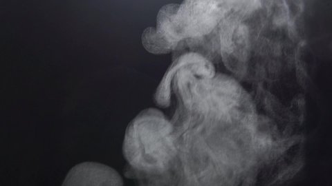 White Steam Ascends Over the Pan. White Steam rises from a large pot that is behind the scenes. Black background. 