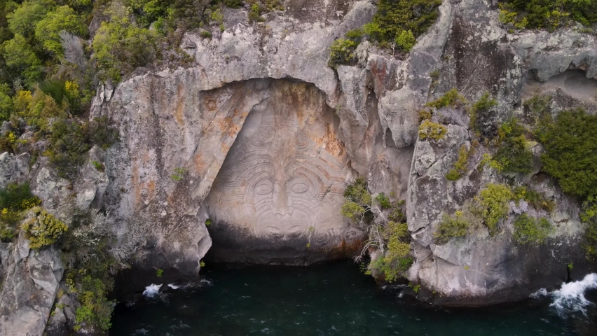 Spectacular Maori tattooed face carved in rocky cliff. Stunning artwork on Lake Taupo lakeside, Aotearoa, New Zealand. aerial drone