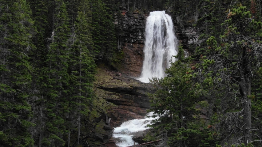 Virginia Falls, Glacier National Park, Montana. Aerial View, Cascade Waterfalls in Conifer Forest. Pull Back Drone Shot