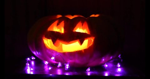 halloween pumpkin glowing in the dark carved with puple bats garlands decoration