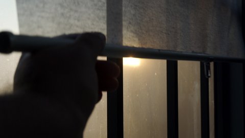 Sun shines through the closed blinds on the window, opening closing roller blind curtain on a frozen balcony window. High quality 4k footage