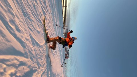 Skilled sportsman in colorful suit skies down along snowy mountain slope under clear blue sky in early cold winter morning. Vertical Video.