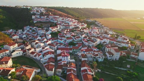 Scenic sunset over a Portuguese village with traditional colourful houses in 4K. Whitewashed traditional windmill in Odeceixe, Aljezur, Portugal, Algarve, near the Nature Park.