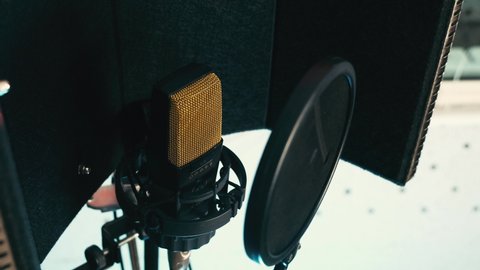Golden grill studio recording microphone with pop and reflection filter in the vocal booth