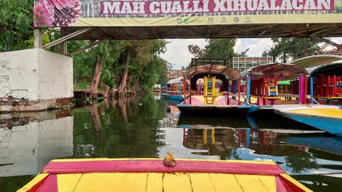 Mexico, September 20, 2019 - Picturesque hyperlapse view of traditional colorful gondola like boats called trajineras moored in calm water of canal in Xochimilco borough o Mexico City