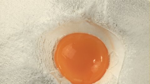 Super slow motion in a pile of flour falls a fresh egg. Top view. Macro background.Filmed on a high-speed camera at 1000 fps. High quality FullHD footage