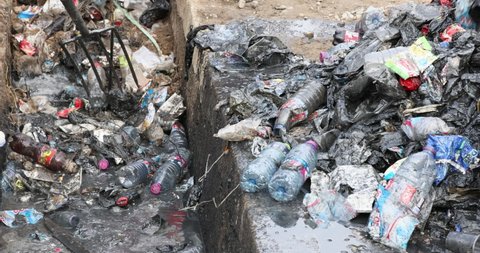 NIMA, GHANA - 23 OCT 2021: Sewer trash garbage cleaning ditch drain poverty area Accra Ghana. Historical congested market residential area. Pollution and garbage. Homes low income poverty of Africa.