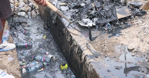 NIMA, GHANA - 23 OCT 2021: Raw sewer cleaning ditch drain poverty area Accra Ghana. Historical congested market residential area. Pollution and garbage. Homes low income poverty of Africa.